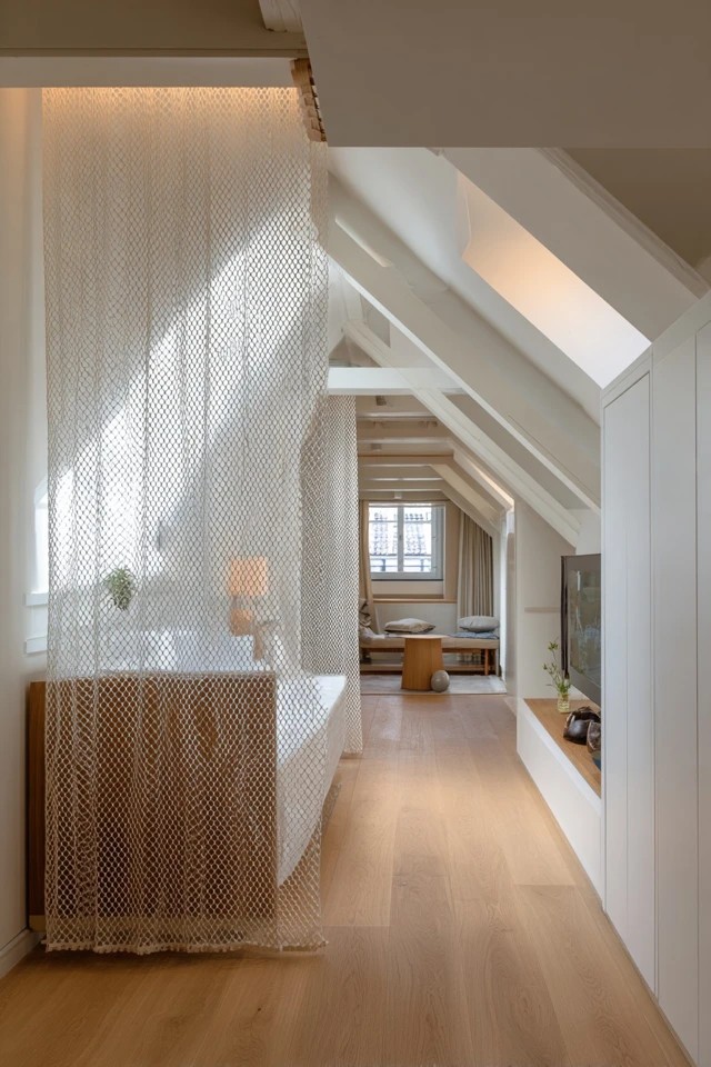 Armchair positioned beside a dormer window creating a comfortable light-filled relaxation corner in an attic apartment