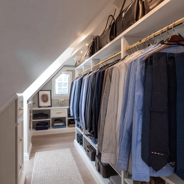 Pull-out trouser rack extending from the wardrobe unit keeping trousers crease-free in an attic walk-in closet
