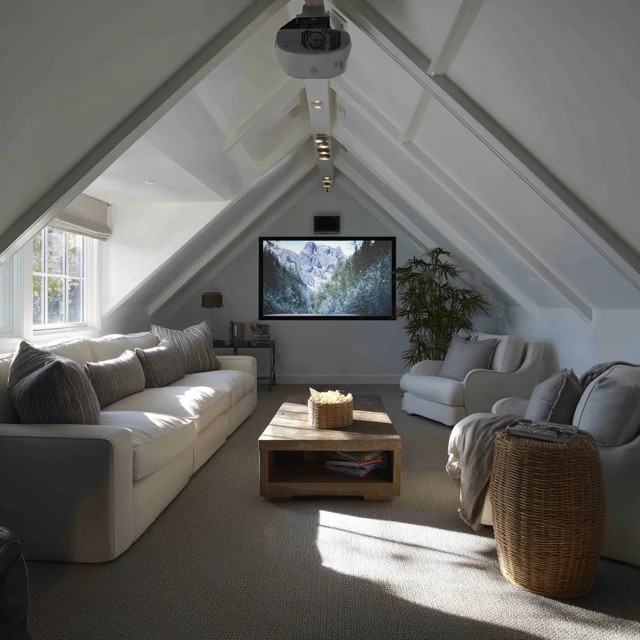 Plush area rug under the seating defining the viewing zone and softening acoustics in an attic TV room